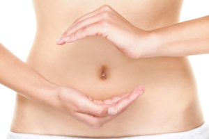 Balanced diet - healthy eating and stomach health concept. Woman holding hands over stomach as yin yang as symbol of healthy balanced diet and health. Young female belly close up.