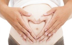 hands of pregnant woman and her husband in heart shape